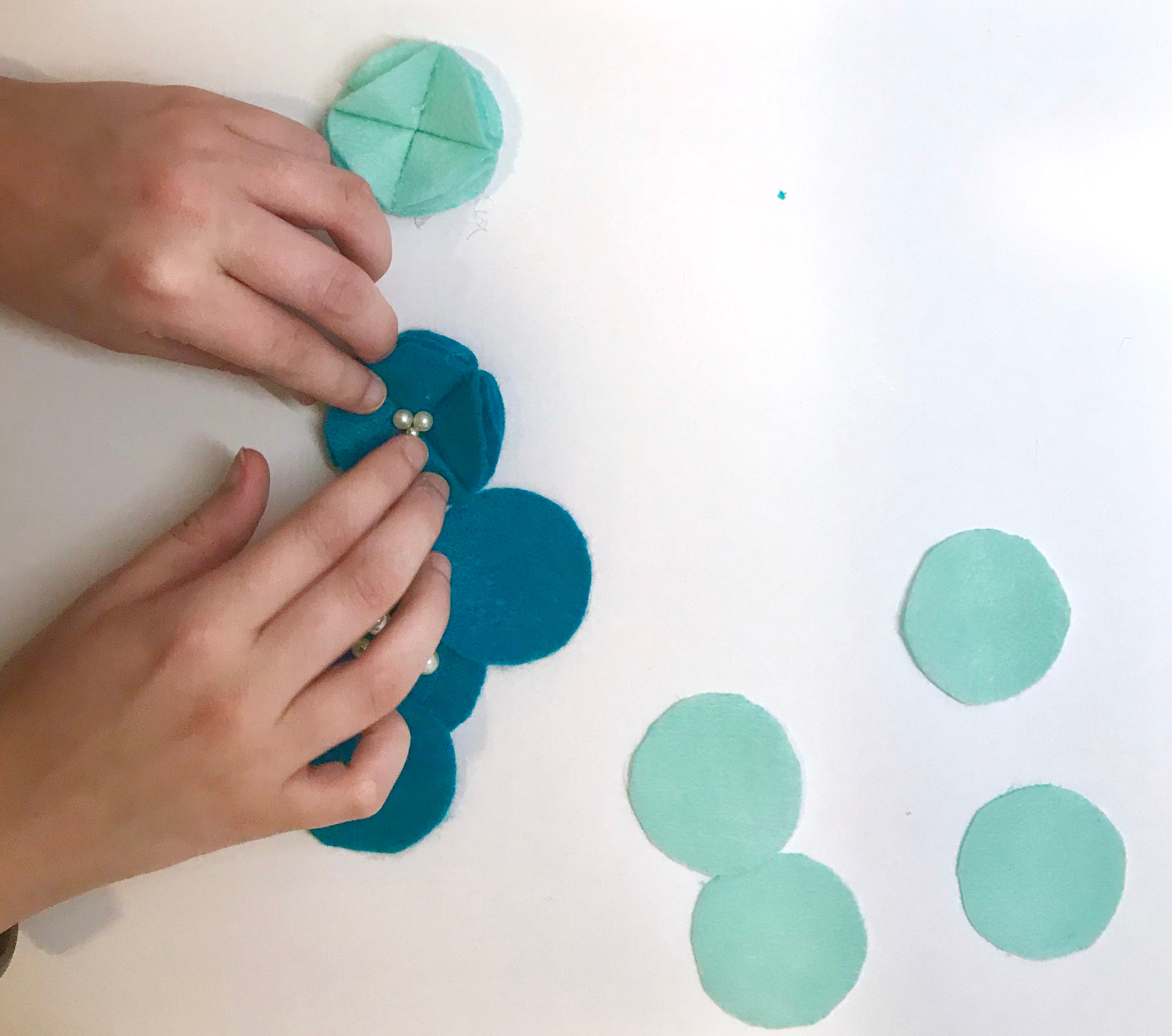 gluing felt flowers together to make a floral name banner for baby's nursery