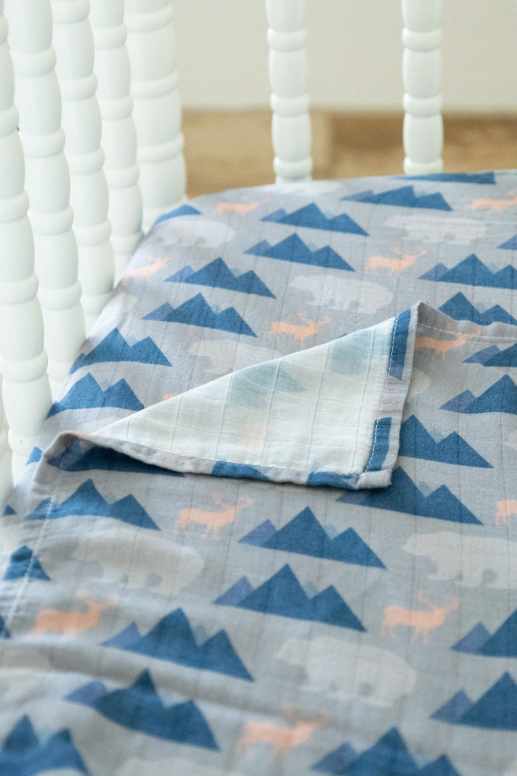 Crib with a blue and gray mountain-patterned quilt