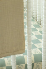 Close-up of a crib with a checkered sheet and teddy bear pattern