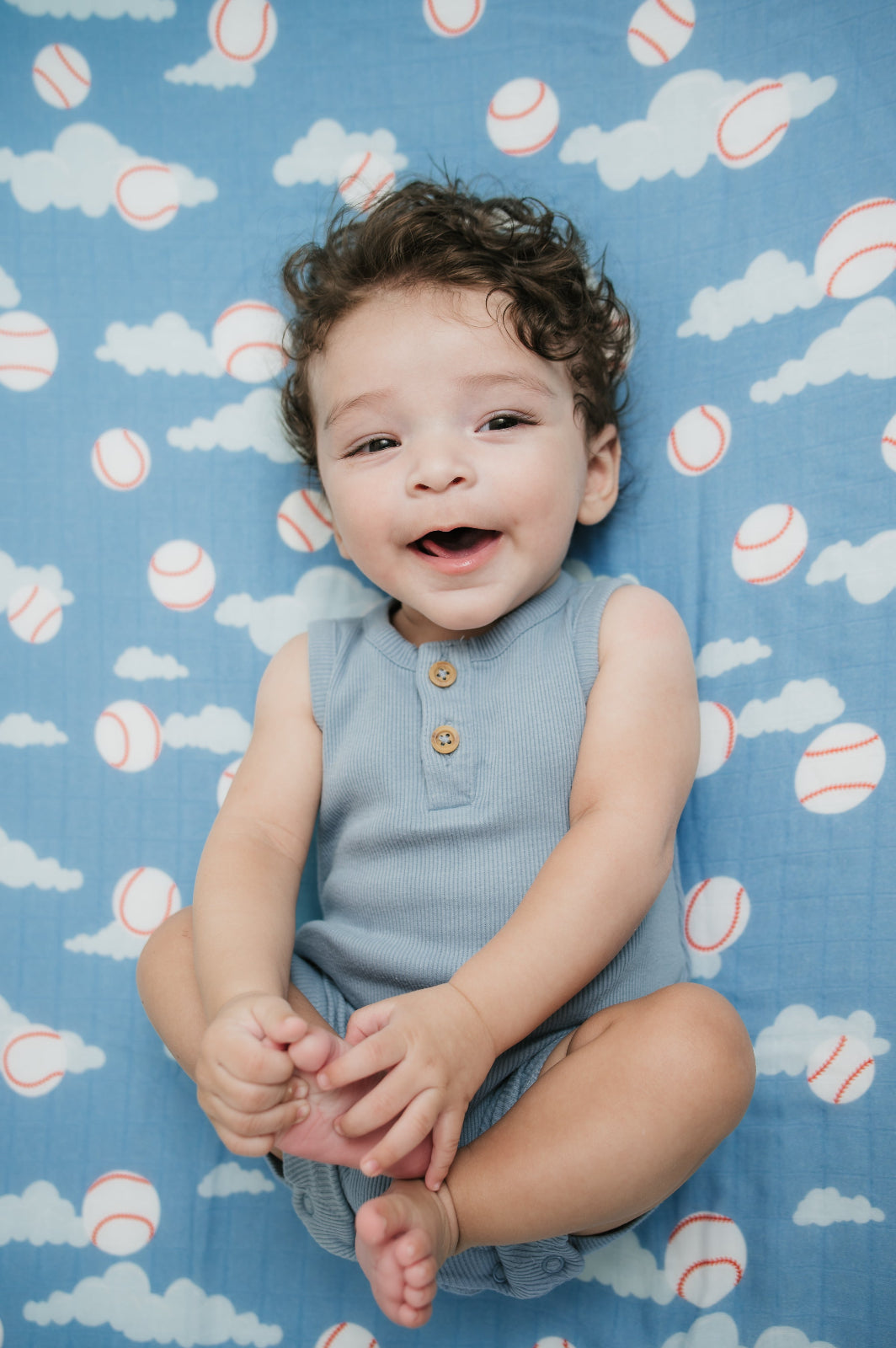 Child lying on a blue blanket with baseball pattern