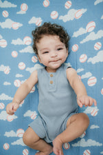 Baby lying on a blue blanket with cloud and baseball pattern