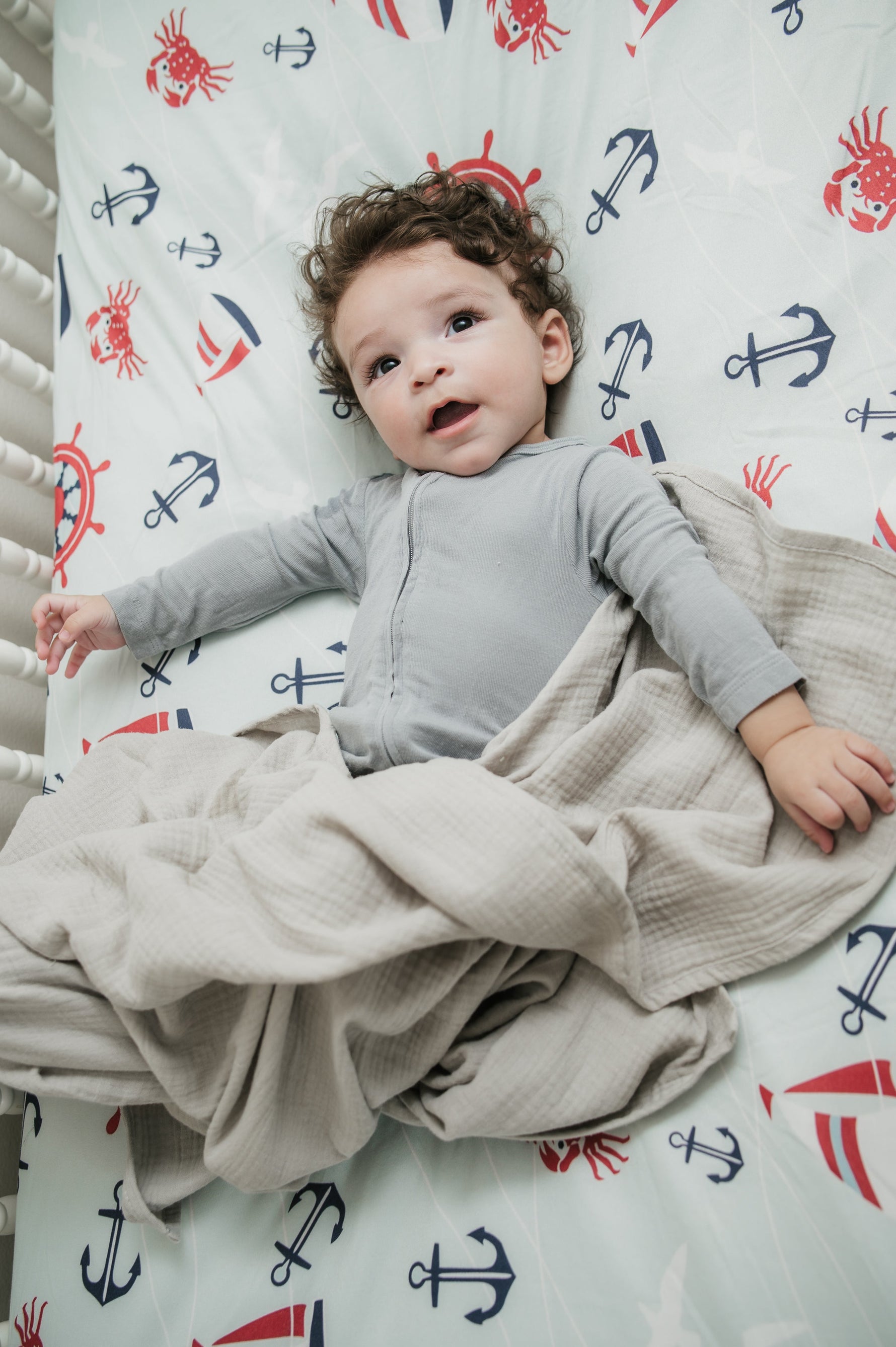 Child lying on a bed with a nautical-themed sheet