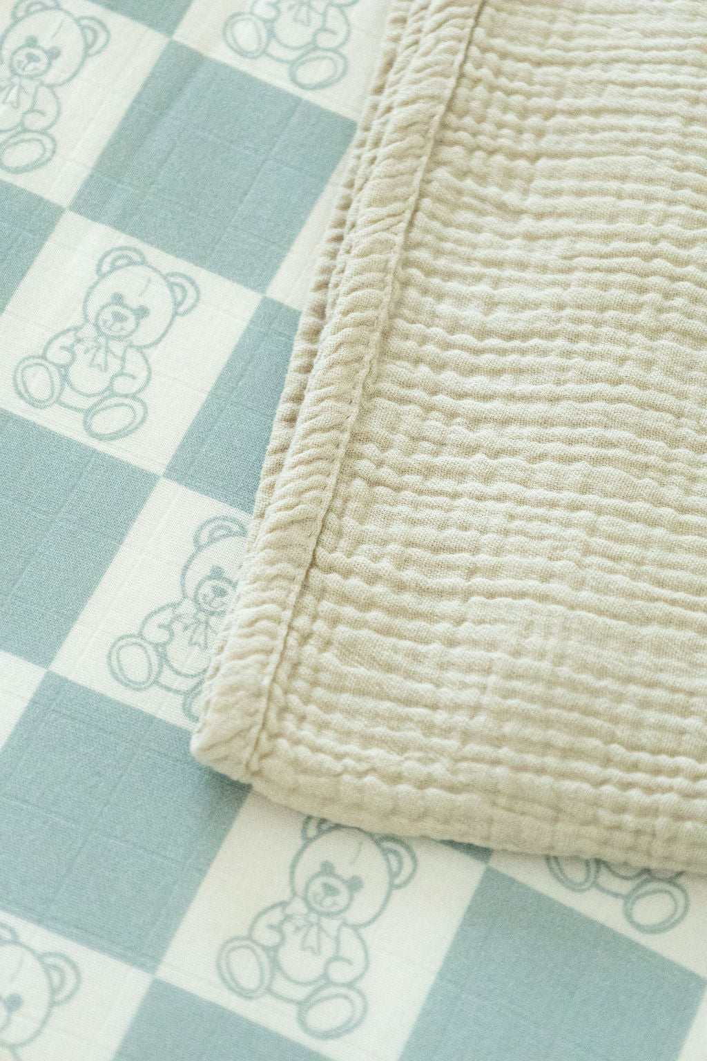 Beige textured blanket on a checkered fabric with teddy bear pattern