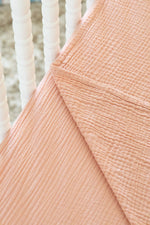 Close-up of textured peach fabric with white woven background