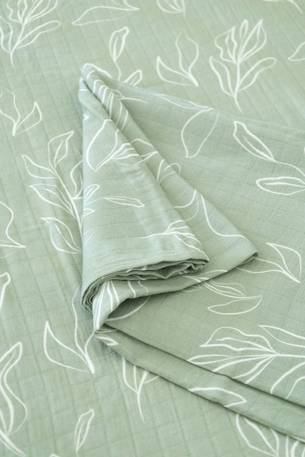Folded fabric with leaf pattern on a light green background