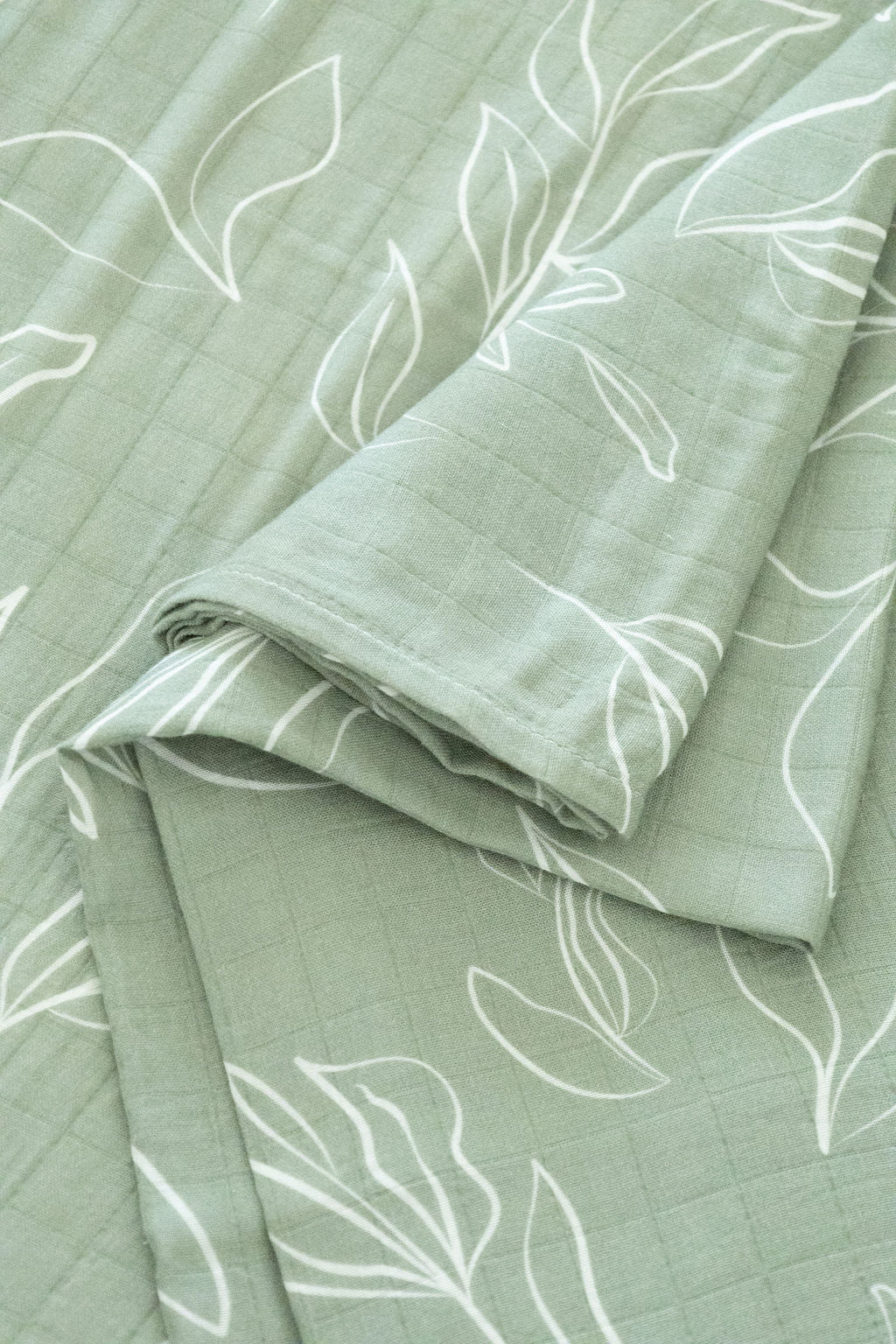Green blanket with white leaf patterns on a matching background