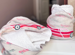race car baby hooded towel featuring multi-colored racecars as a pattern on pastel khaki background color - features a bright red 'toy car' styled race car